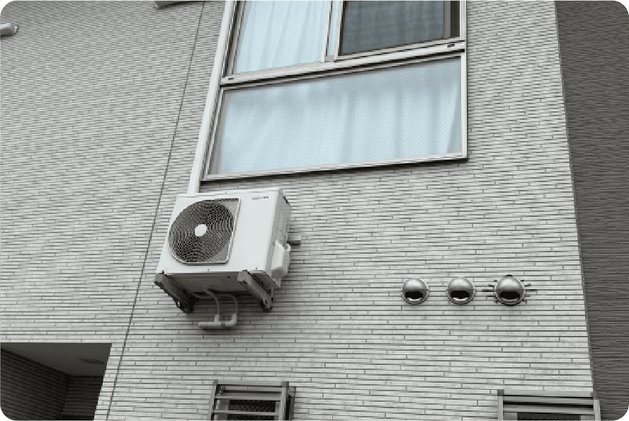 窓下の外壁にブラケットで取り付けられた室外機の例。