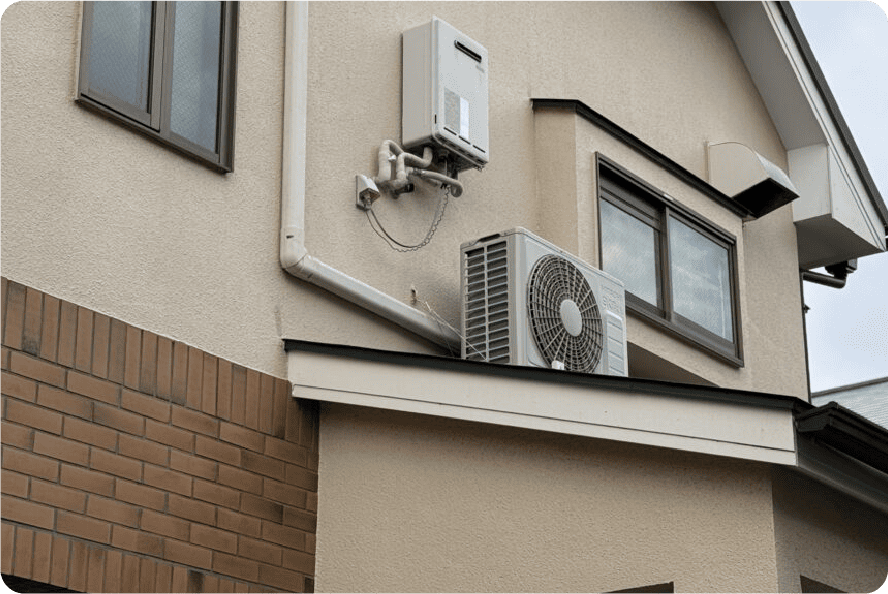 下屋の上にブラケットで設置された壁面室外機の例。