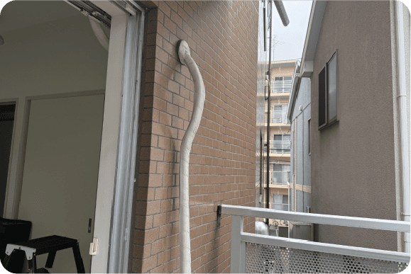 外壁に沿って下方向へ伸びる屋外配管の例。
